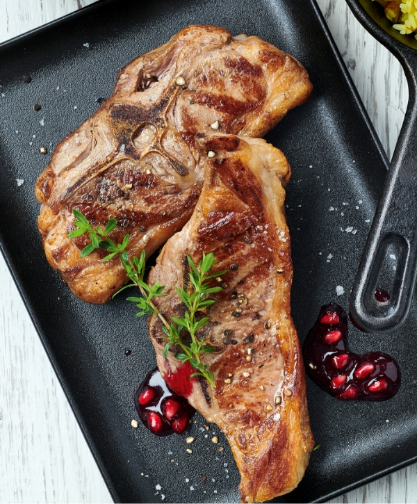 Zwei gebratene Lammkoteletts auf dem Blech mit Granatapfelkernen und Gewürzen