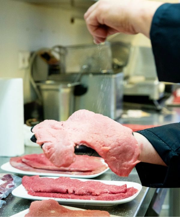 Ein Stück Kalbfleisch wird gesalzen